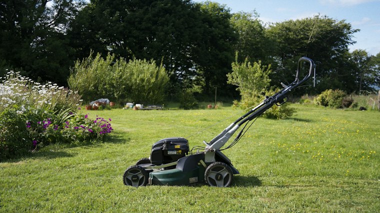 Cortacésped sobre el césped recién segado de un jardín durante el mantenimiento periódico